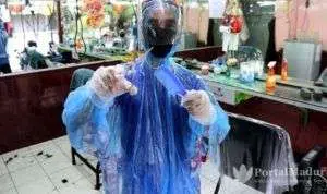 Lindungi Diri, Tukang Cukur Pakai APD Covid-19
