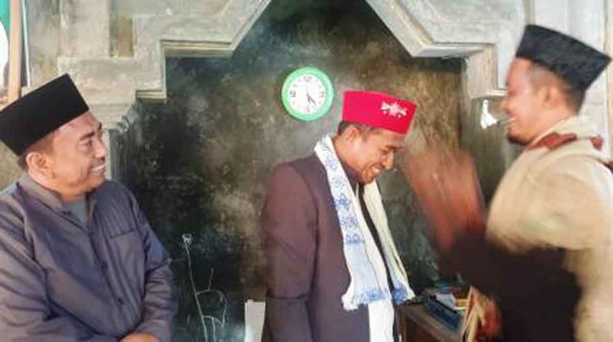 Ketua GMNU Madura saat memakaikan songkok warna merah bertuliskan NU kepada Achmad Fauzi