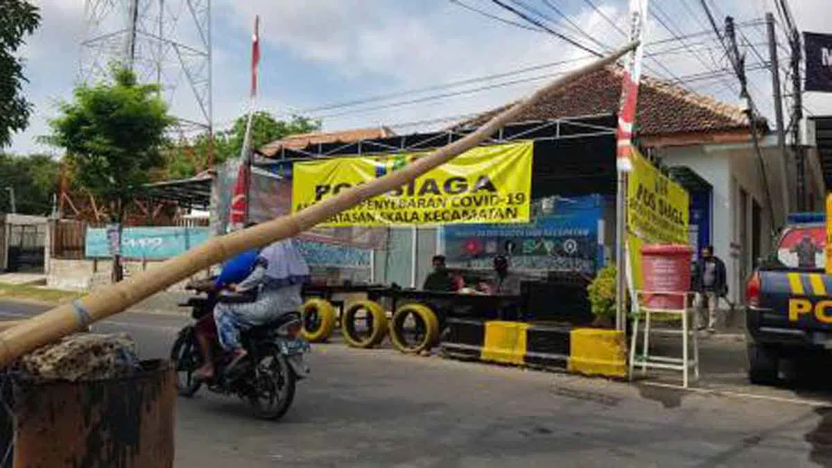 Simpang tiga Jalan Raya Kecamatan Saronggi yang menjadi pintu masuk utama ke wilayah tujuh desa dijaga ketat oleh petugas gabungan. Akses jalan diberi palang bambu. (@portalmadura.com)