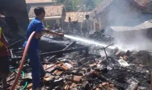 Proses pembasahan api di lokasi kebakaran kandang sapi dan dapur (Foto. Rafi @portalmadura.com)