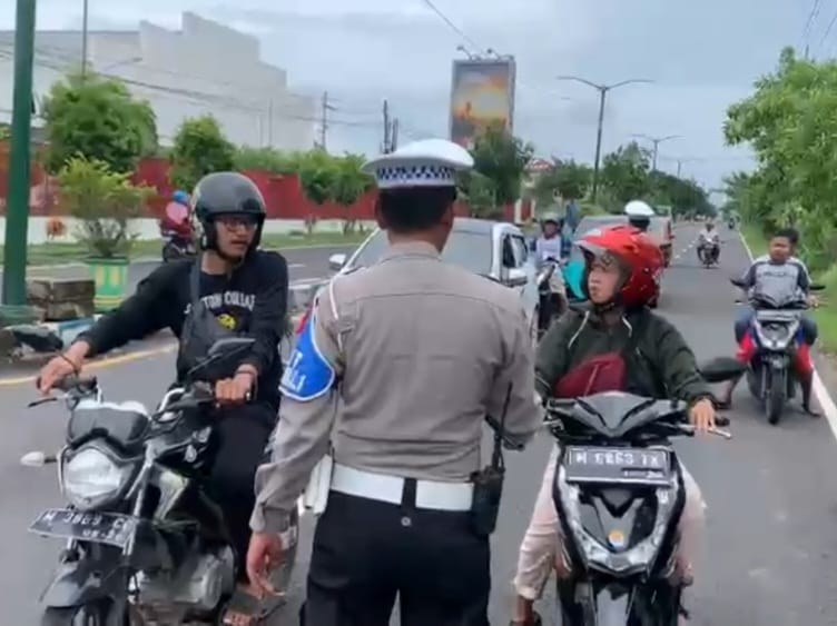 Anggota Satlantas Polres Sumenep siaga di kawasan akses jalan protokol Sumenep-Surabaya, tepatnya di Desa Patean Kecamatan Batuan, yang tergenang air setinggi lutut, Minggu (1/1). (IST/POLRES SUMENEP